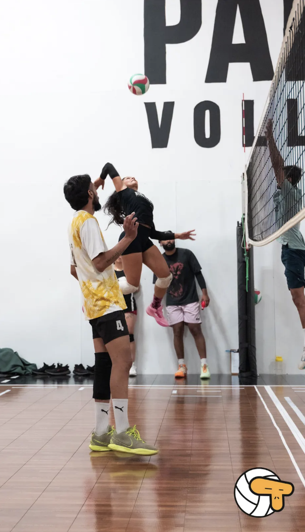 Female volleyball athlete jumping to spike the ball at the net
